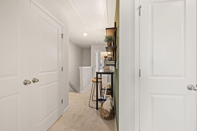 hall with baseboards, an upstairs landing, and light colored carpet