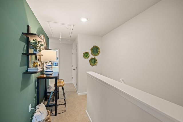 hallway with attic access, light carpet, baseboards, and an upstairs landing