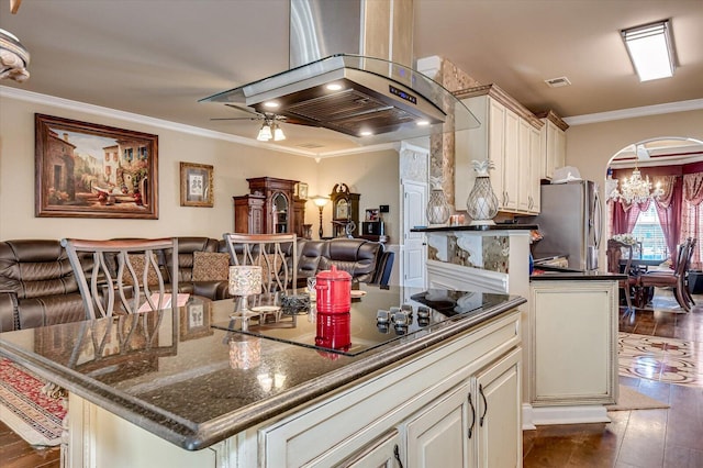 kitchen with a center island, stainless steel fridge, dark stone counters, island range hood, and black electric stovetop