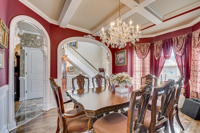 dining room with beam ceiling, an inviting chandelier, ornamental molding, and hardwood / wood-style floors