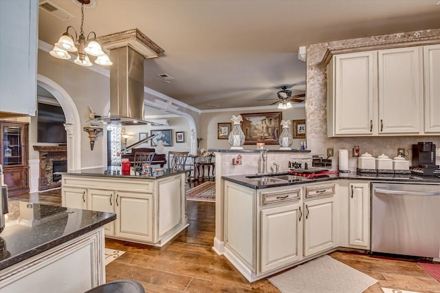 kitchen featuring kitchen peninsula, cream cabinets, stainless steel dishwasher, and decorative light fixtures