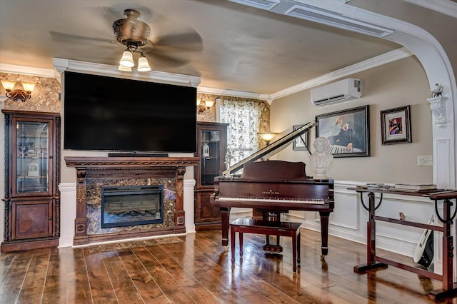 misc room featuring ceiling fan, a wall mounted air conditioner, crown molding, hardwood / wood-style floors, and a fireplace