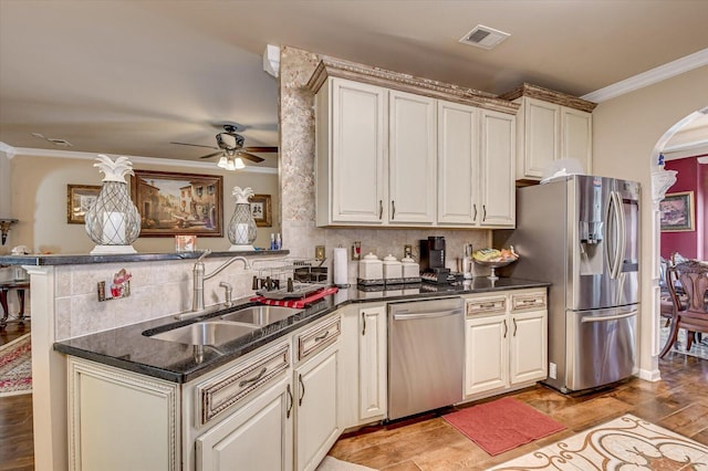 kitchen with kitchen peninsula, crown molding, sink, and appliances with stainless steel finishes