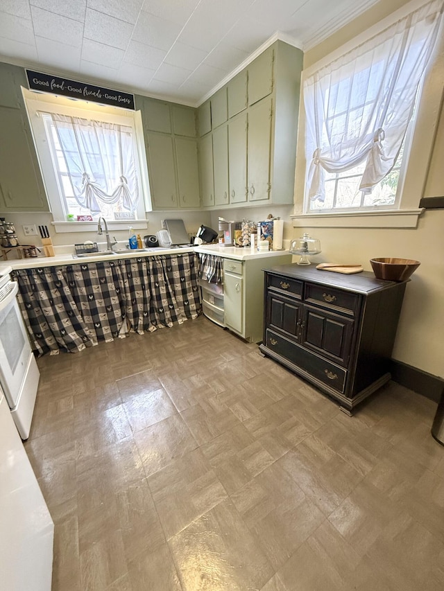 kitchen featuring stove, sink, ornamental molding, and green cabinets