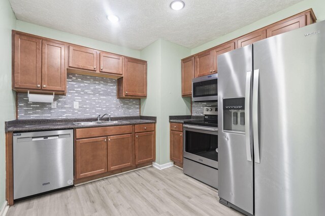 2954 Celeste Dr, Hephzibah, GA 30815 - kitchen featuring appliances with stainless steel finishes, a sink, light wood-style flooring, decorative backsplash, and a textured ceiling