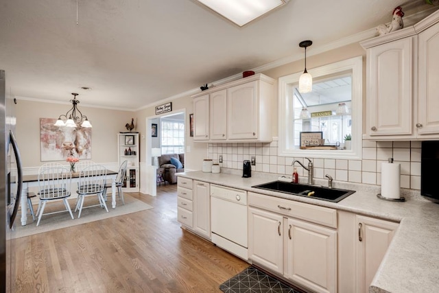 kitchen featuring hanging light fixtures, dishwasher, sink, and light hardwood / wood-style flooring