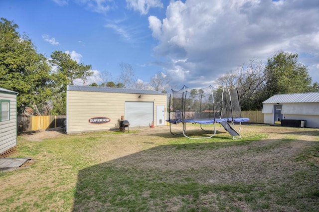 view of yard with a trampoline and an outbuilding