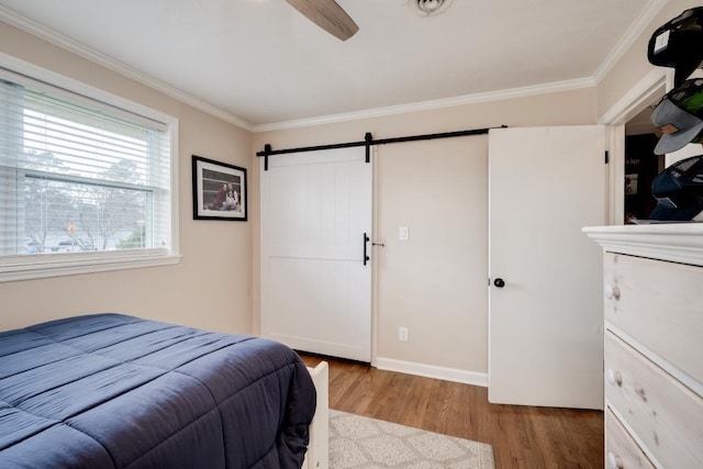 bedroom with wood-type flooring, a barn door, and ornamental molding