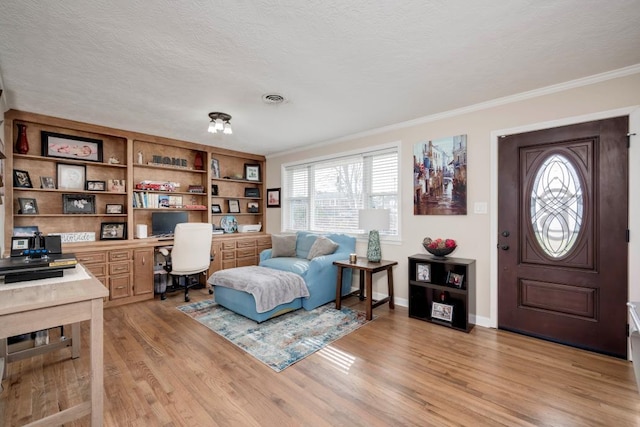 office space with built in desk, ornamental molding, a textured ceiling, and light wood-type flooring