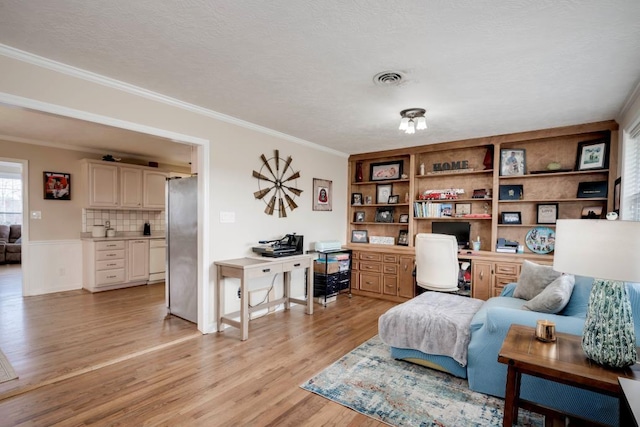 living area featuring ornamental molding, built in desk, a textured ceiling, and light hardwood / wood-style floors