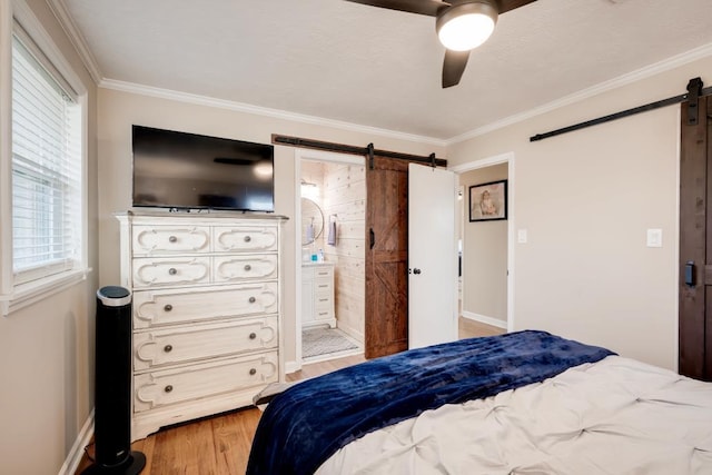 bedroom with ceiling fan, ornamental molding, a barn door, and light hardwood / wood-style floors