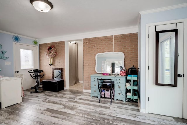 interior space featuring plenty of natural light, ornamental molding, brick wall, and light wood-type flooring