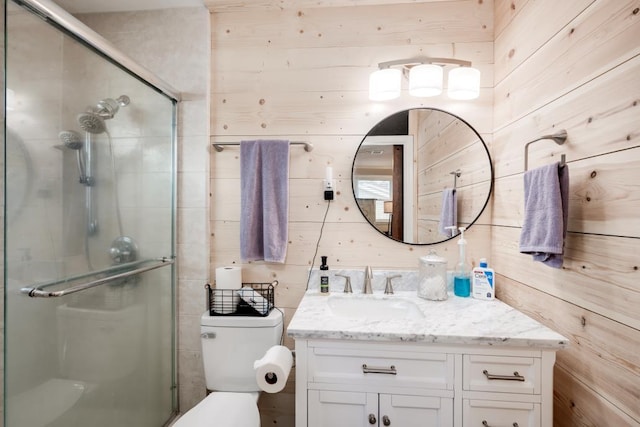 bathroom featuring an enclosed shower, vanity, wooden walls, and toilet