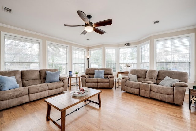 living room featuring crown molding, a wealth of natural light, and light hardwood / wood-style flooring