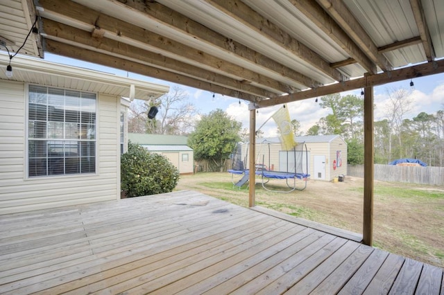 deck featuring a yard, a trampoline, and a storage unit