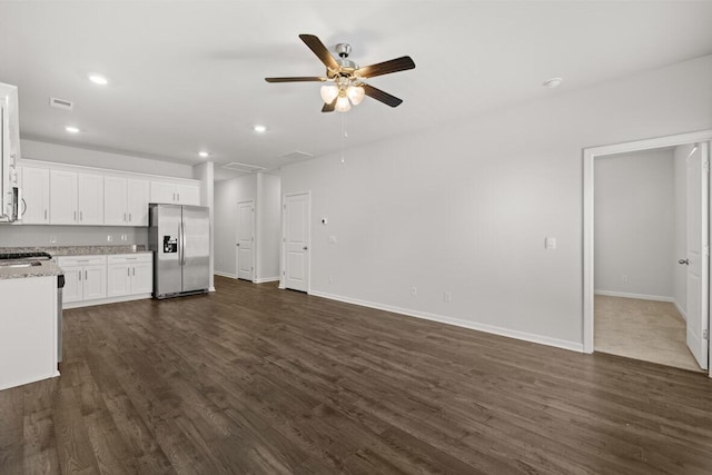 kitchen featuring light stone countertops, stainless steel refrigerator with ice dispenser, ceiling fan, dark wood-type flooring, and white cabinets