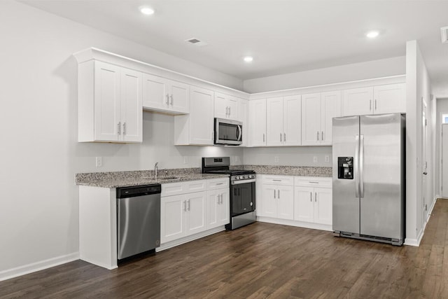 kitchen with white cabinetry, sink, stainless steel appliances, light stone counters, and dark hardwood / wood-style flooring