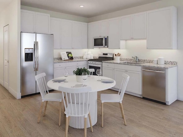 kitchen with white cabinetry, sink, stainless steel appliances, and light hardwood / wood-style flooring