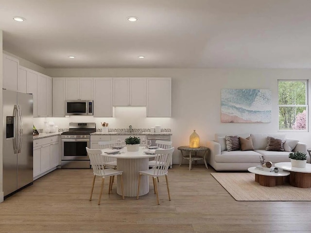 kitchen featuring light hardwood / wood-style floors, a kitchen bar, white cabinetry, and stainless steel appliances