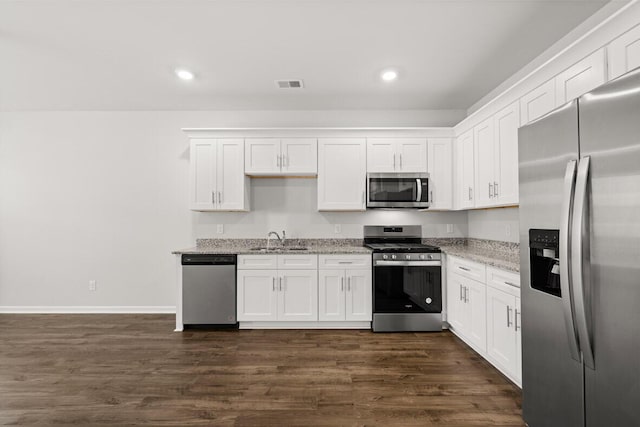 kitchen featuring light stone countertops, stainless steel appliances, white cabinets, and sink