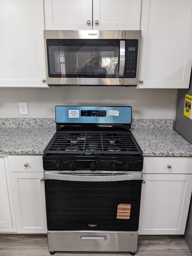 3332 Hillis Rd, Augusta, GA 30906 - kitchen view of appliances with stainless steel finishes, white cabinetry, wood finished floors, and light stone counters