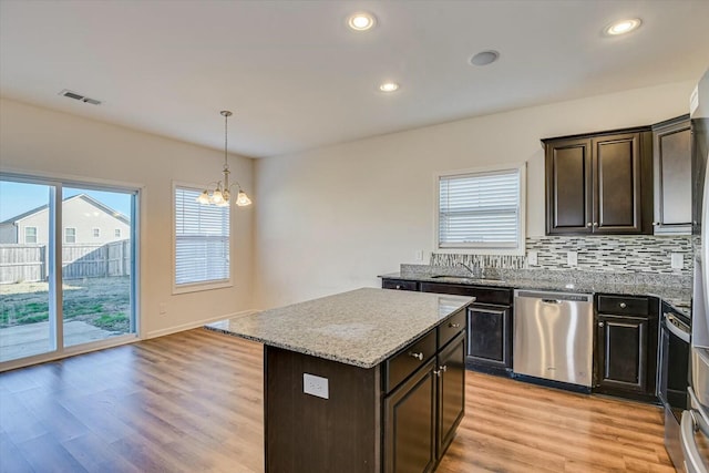 kitchen with dishwasher, a center island, an inviting chandelier, light hardwood / wood-style floors, and decorative light fixtures