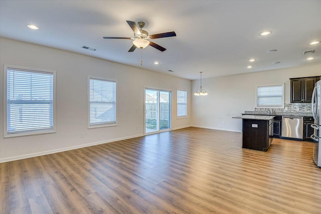 kitchen featuring light wood-type flooring, a wealth of natural light, ceiling fan with notable chandelier, stainless steel appliances, and decorative light fixtures