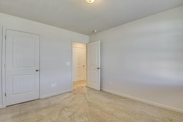 unfurnished bedroom with a closet and light colored carpet