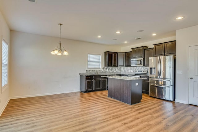 kitchen with light hardwood / wood-style floors, decorative light fixtures, a kitchen island, stainless steel appliances, and a chandelier