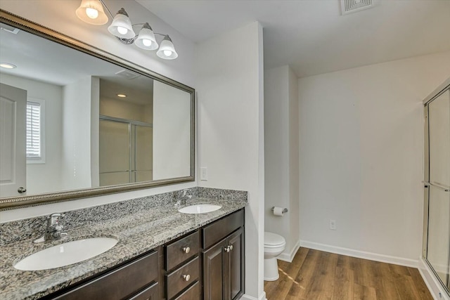 bathroom with a shower with door, vanity, hardwood / wood-style floors, and toilet