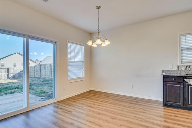 unfurnished dining area featuring light wood-type flooring and a chandelier