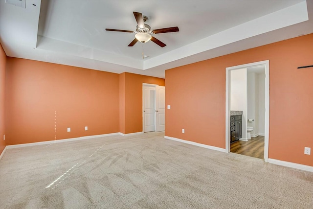 carpeted empty room featuring a tray ceiling and ceiling fan