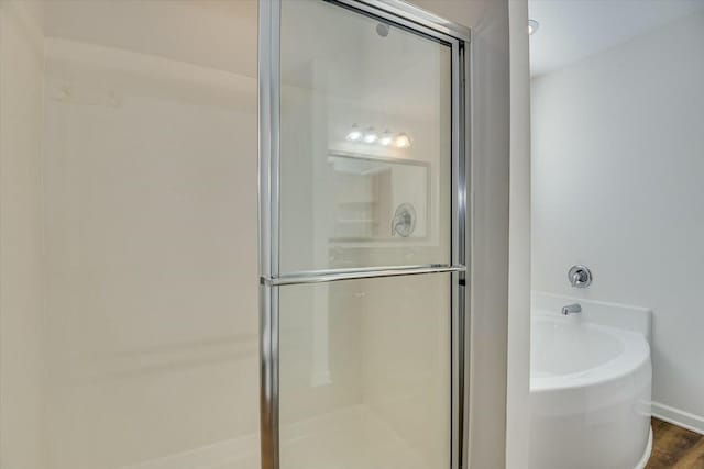 bathroom with shower with separate bathtub and wood-type flooring