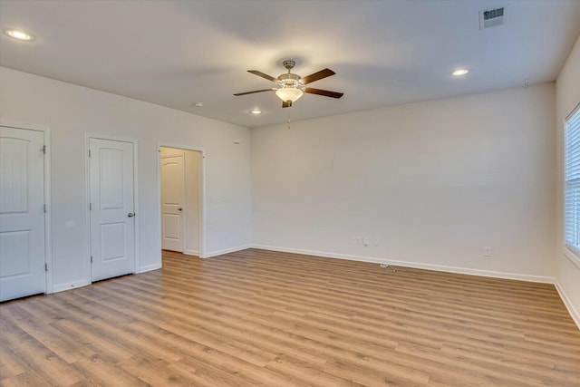 unfurnished bedroom featuring ceiling fan, light hardwood / wood-style flooring, and two closets