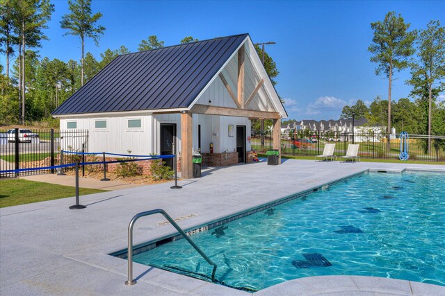 community pool featuring a patio, an outdoor structure, and fence