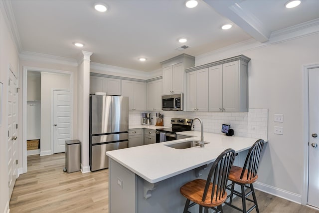 kitchen featuring visible vents, a kitchen breakfast bar, a sink, appliances with stainless steel finishes, and gray cabinetry