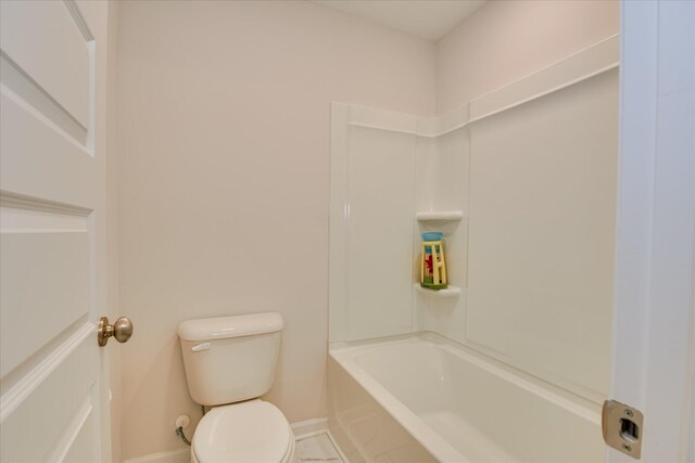 bathroom with baseboards, toilet, and  shower combination