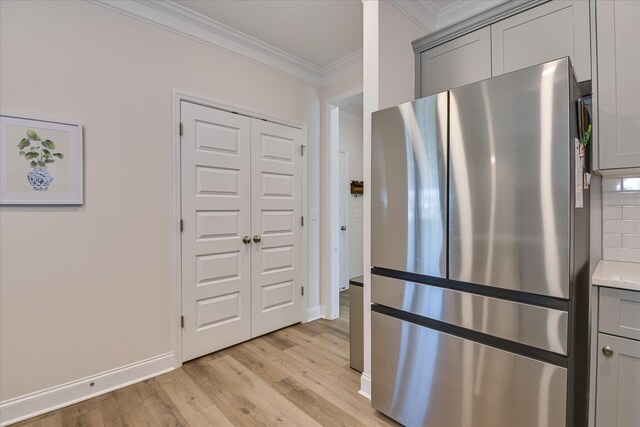 kitchen with crown molding, gray cabinets, freestanding refrigerator, baseboards, and light wood-type flooring