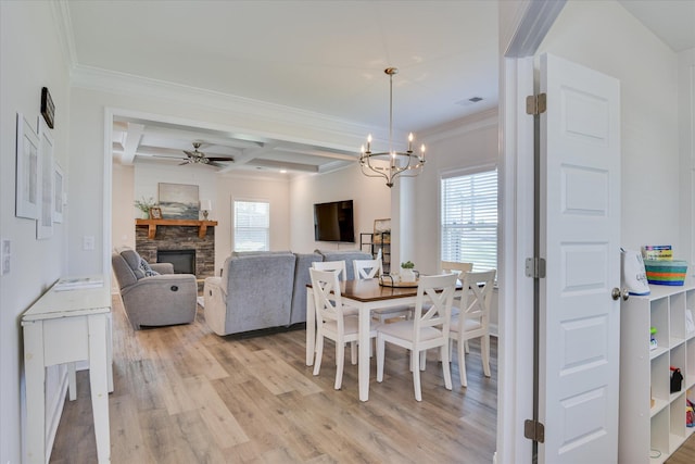 dining area with visible vents, beamed ceiling, a stone fireplace, light wood-type flooring, and coffered ceiling