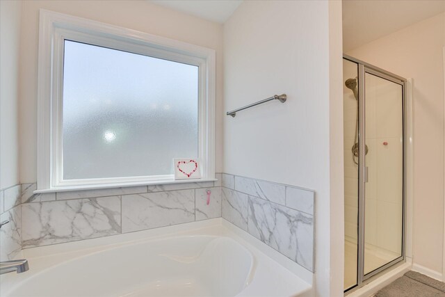 bathroom featuring plenty of natural light, a stall shower, and a bath