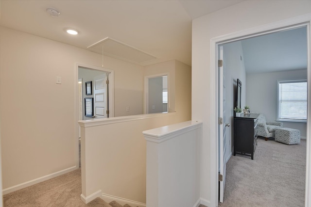 corridor featuring baseboards, an upstairs landing, light carpet, and attic access