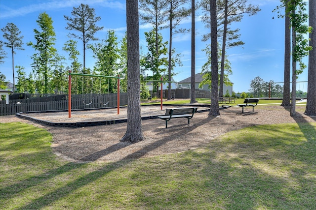 view of property's community featuring a yard, fence, and playground community