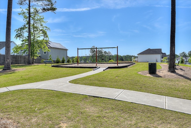 view of property's community featuring a lawn, fence, and playground community