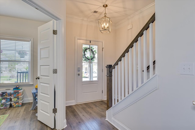 foyer featuring crown molding, a notable chandelier, wood finished floors, and stairway