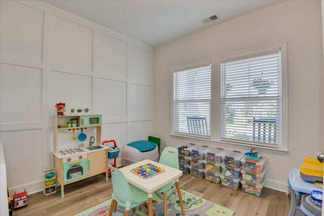 recreation room with baseboards, visible vents, and light wood-type flooring