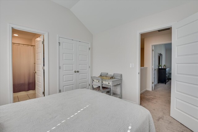 bedroom featuring visible vents, a closet, lofted ceiling, baseboards, and ensuite bathroom