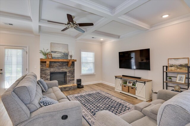 living room featuring visible vents, beam ceiling, light wood-style floors, a stone fireplace, and a ceiling fan