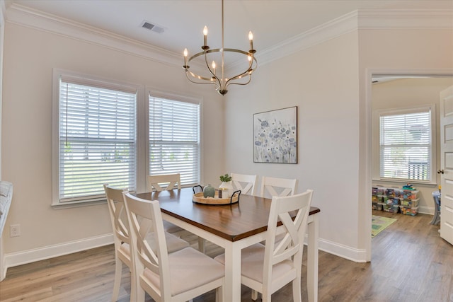 dining area with visible vents, a healthy amount of sunlight, an inviting chandelier, and light wood finished floors
