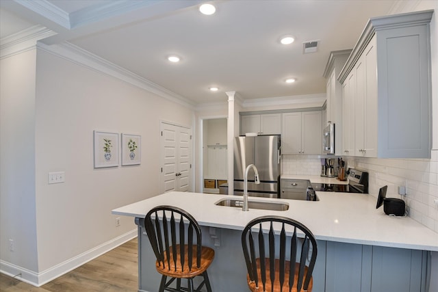 kitchen featuring gray cabinets, appliances with stainless steel finishes, tasteful backsplash, light countertops, and a peninsula