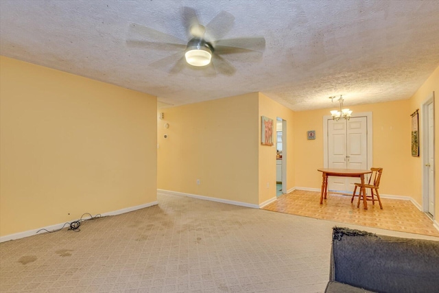 interior space with carpet flooring, ceiling fan with notable chandelier, and a textured ceiling